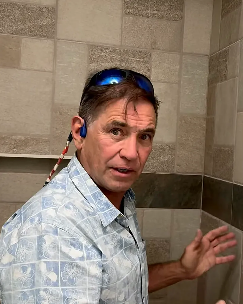 Tom McKay explaining a flip house's new tile shower to the camera