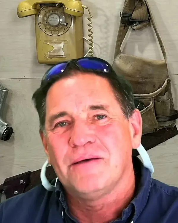 Tom McKay, your phone consultation expert, wearing a headset beneath the vintage wall phone in his office