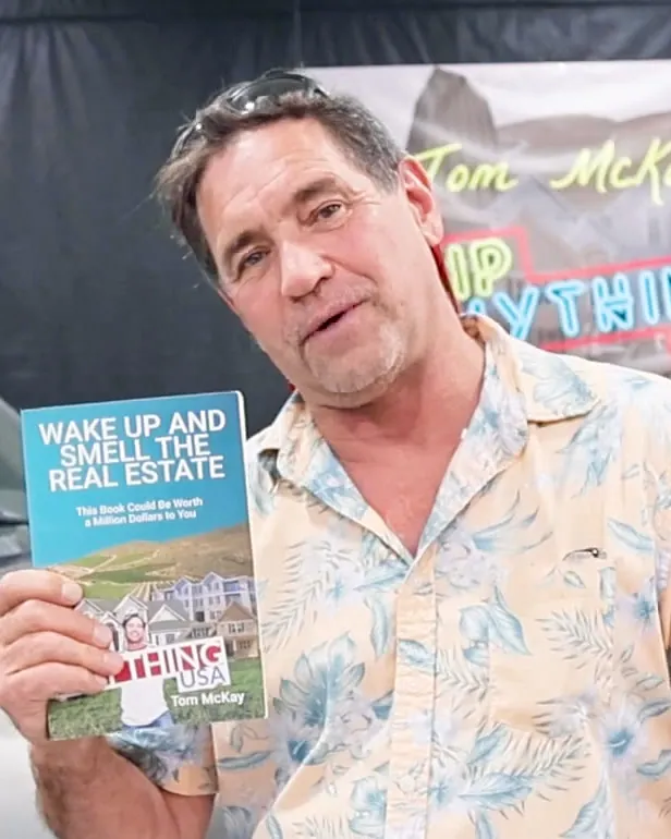 Tom McKay, author of Wake Up and Smell the Real Estate, holding a copy of the book