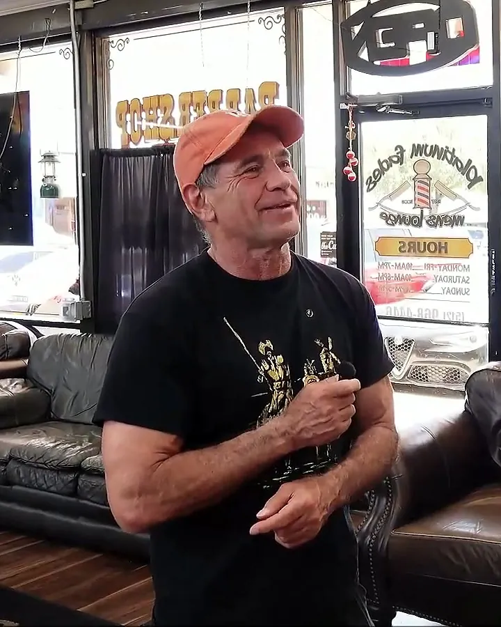 Tom McKay smiling and listening in a tenant's barber shop