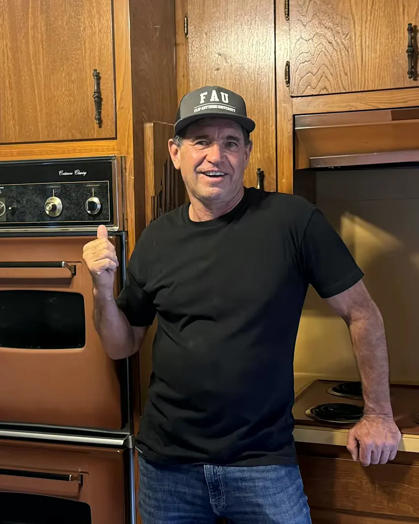 Tom McKay giving a thumbs-up beside the original copper wall ovens of a 1974 house